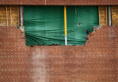 Big hole in the wall covered by a green tarp