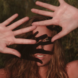 Close-up portrait of young woman shielding eyes during sunny day