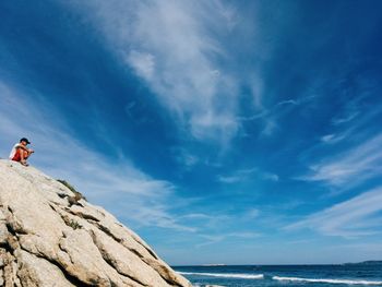 Low angle view of man on rock against sea
