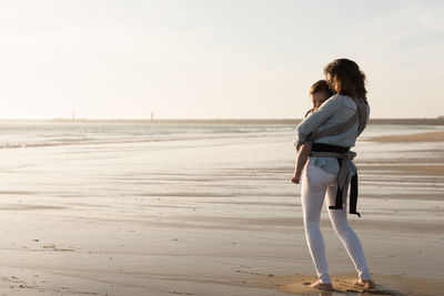 Mother carrying son while walking at beach