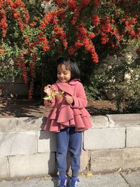 Full length of a smiling girl standing against plants