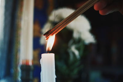 Close-up of human hand lit incandescent with candle to pray