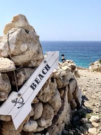 Text on rock by sea against sky