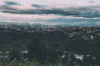 Aerial view of city against cloudy sky