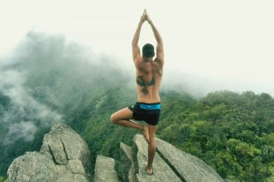 Rear view of man performing tree pose on mountains