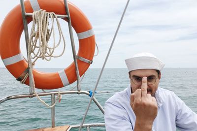 Portrait of man in boat on sea against sky