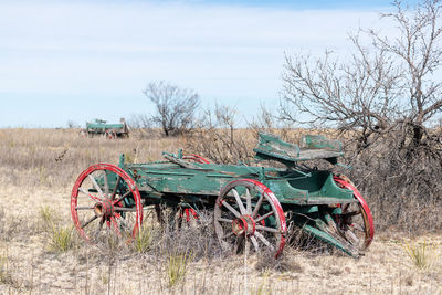 Abandoned cart on field against sky