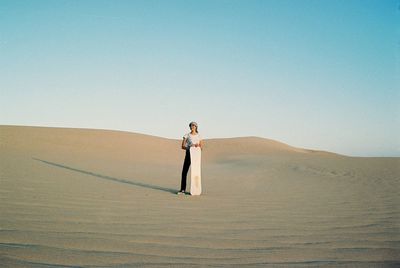 Full length of man standing on desert against clear sky