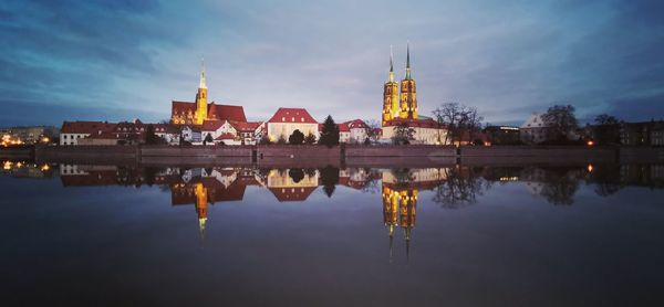 Reflection of illuminated buildings in lake against sky