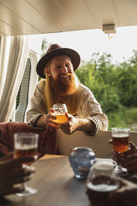 Bearded man with beer glass talking with friends in motor home