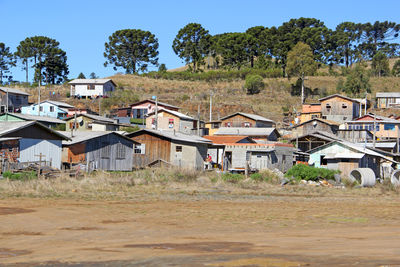 Houses on field by buildings against clear sky