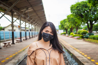 Portrait of young woman standing on railroad track