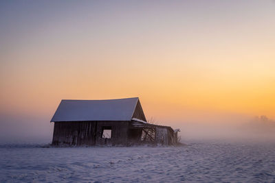 House on sea against sky during sunset