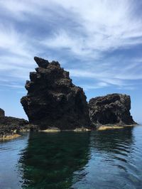 Rock formation by sea against sky