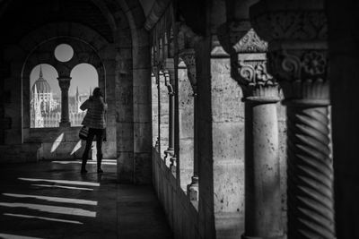 Rear view full length of woman in corridor looking at hungarian parliament building