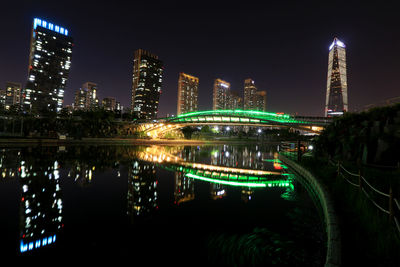 Illuminated modern buildings in city against sky at night