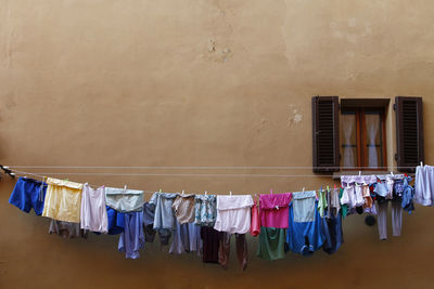 Clothes drying on clothesline by beige wall