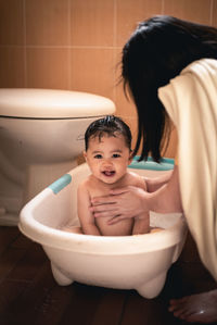 Portrait of happy woman sitting in bathroom at home