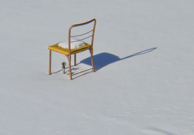 Abandoned yellow chair on pipe in snow field