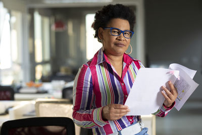 Portrait of woman standing against paper