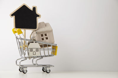 Model house and blackboard in shopping cart against white background