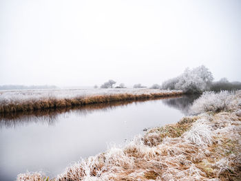 Scenic view of lake against clear sky during winter