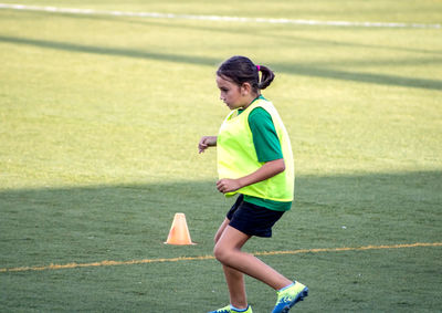 Side view of girl exercising on sports field