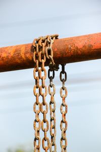 Close-up of rusty chain hanging against sky