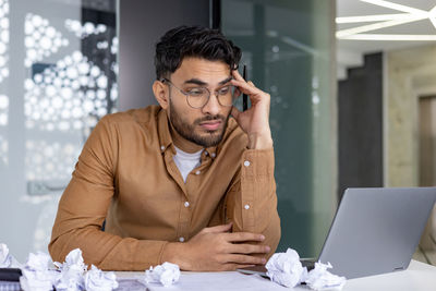 Young man using mobile phone while sitting at home