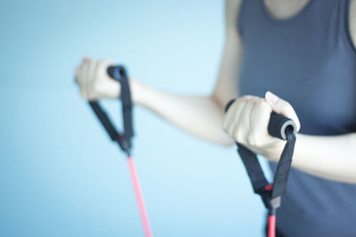 Midsection of woman exercising with resistance band in gym