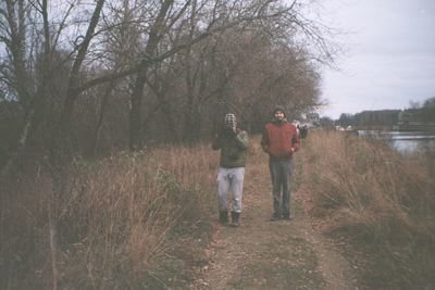 People standing by tree against sky