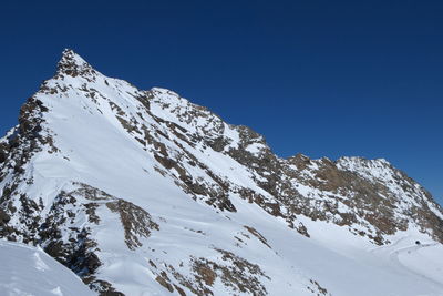 Low angle view of snowcapped mountain against blue sky