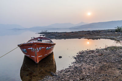 Boat in sea against sky during sunset