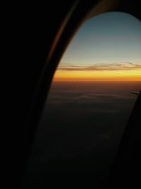 Close-up of airplane wing against sky at sunset