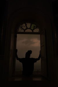 Rear view of man standing by window