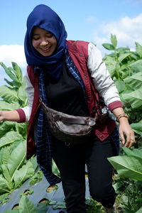 Portrait of young woman standing amidst plants