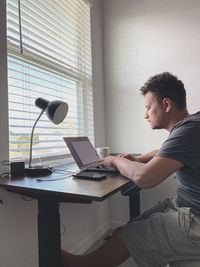 Side view of man working by using laptop at home