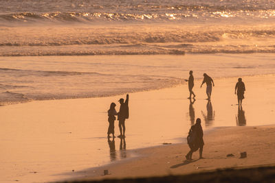 Silhouette woman walking at beach during sunset