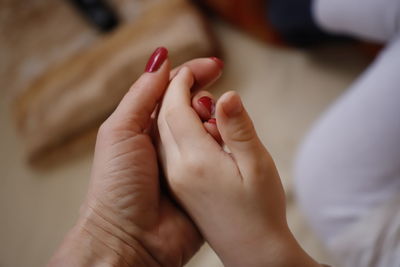 Close-up of mother holding hand of daughter