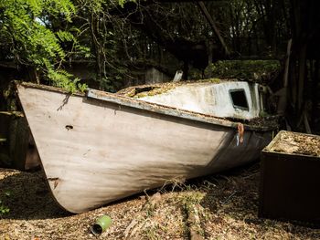 Abandoned boat moored on field in forest