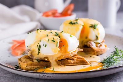 Eggs benedict and bacon on a crispy waffle on a plate for homemade breakfast