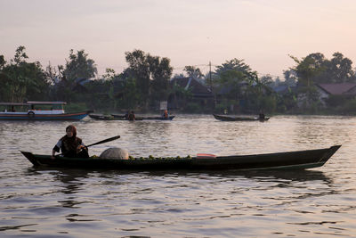 People on boat in river against sky