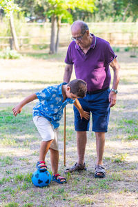 Grandfather and grandson playing football in the park