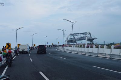 Vehicles on road against sky in city