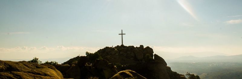 Cross on mountain peak against sky