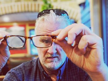 Portrait of man looking through eyeglasses at home