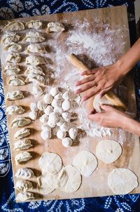 Cropped hands of person rolling dough on cutting board