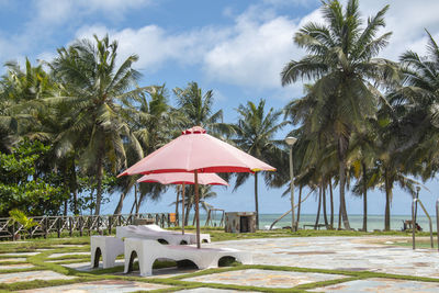 Gazebo by palm trees on beach against sky