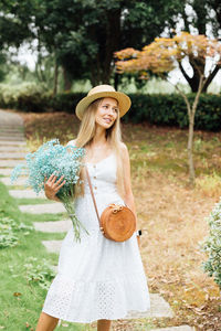 Young woman wearing hat standing against trees