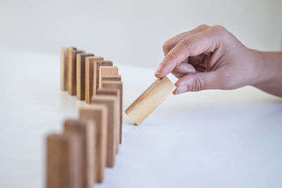 Cropped hand arranging wooden block over white background